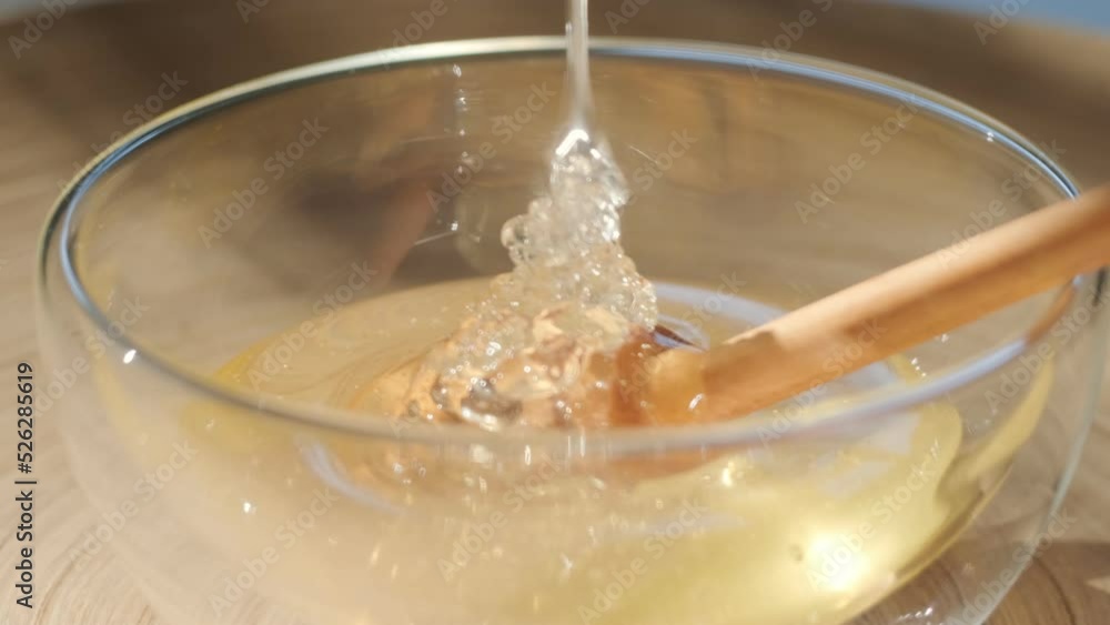Honey dripping, pouring from honey dipper in a glass bowl. Close-up. Organic Thick honey dipping from the wooden honey spoon, closeup. 4K UHD video footage. Slow motion Honey dripping, pouring from honey dipper in a glass bowl. Close-up. Organic Thick honey dipping from the wooden honey spoon, closeup. 4K UHD video footage. Slow motion