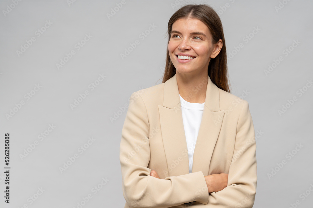 Portrait of dreamy smiling businesswoman with crossed hands on gray background with copy space Portrait of dreamy smiling businesswoman with crossed hands on gray background with copy space