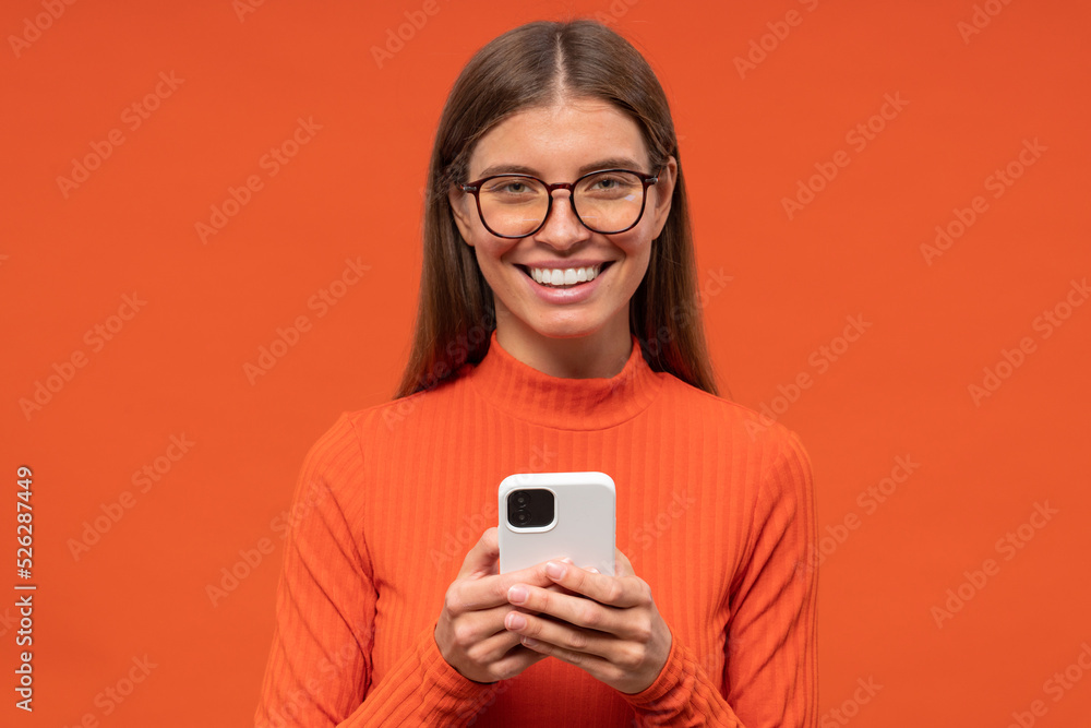 Woman reading funny post on social media app on phone isolated on orange background Woman reading funny post on social media app on phone isolated on orange background
