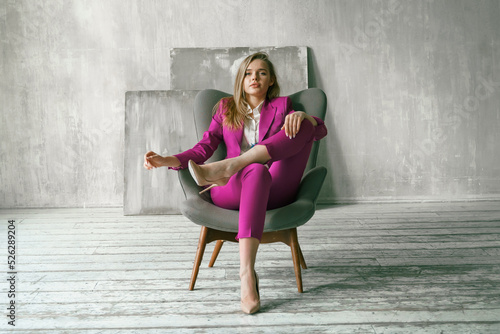 Young businesswoman. Beautiful woman director, head, general manager, ceo in astylish bright business pink, fuchsia color suit at photoshoot in armchair. Business purposeful ambitious girl careerist photo