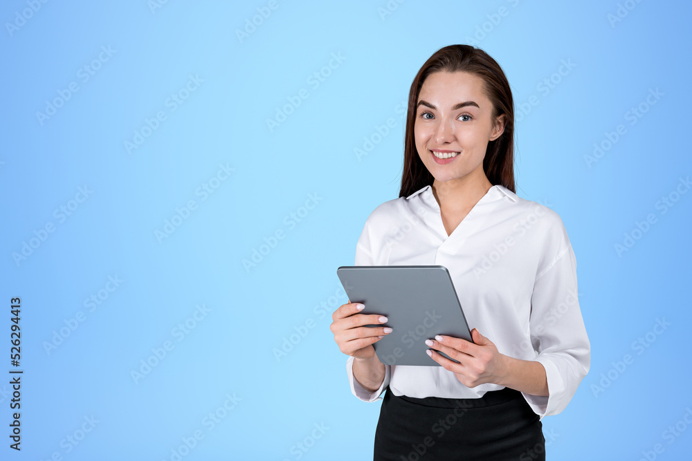 Smiling businesswoman wearing formal wear is standing holding ta Smiling businesswoman wearing formal wear is standing holding ta