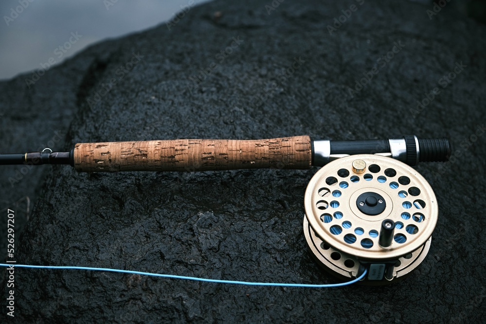 Closeup of an old Shakespeare fly rod design with a gold reel on a rock  Stock Photo