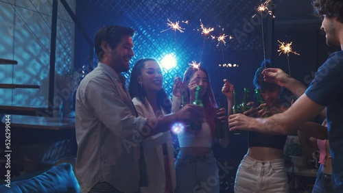 Diverse  young people clinking beer and waving sparkler on night party