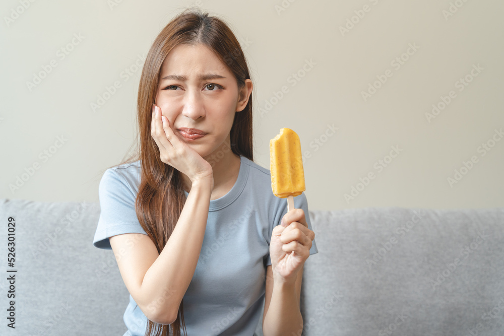 Face expression suffering from sensitive teeth, Asian young woman touching cheek Face expression suffering from sensitive teeth, Asian young woman touching cheek