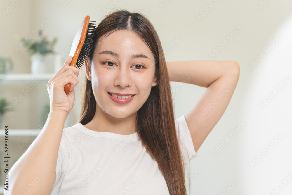 Happy asian woman brushing hair by wooden comb in the morning. Happy asian woman brushing hair by wooden comb in the morning.