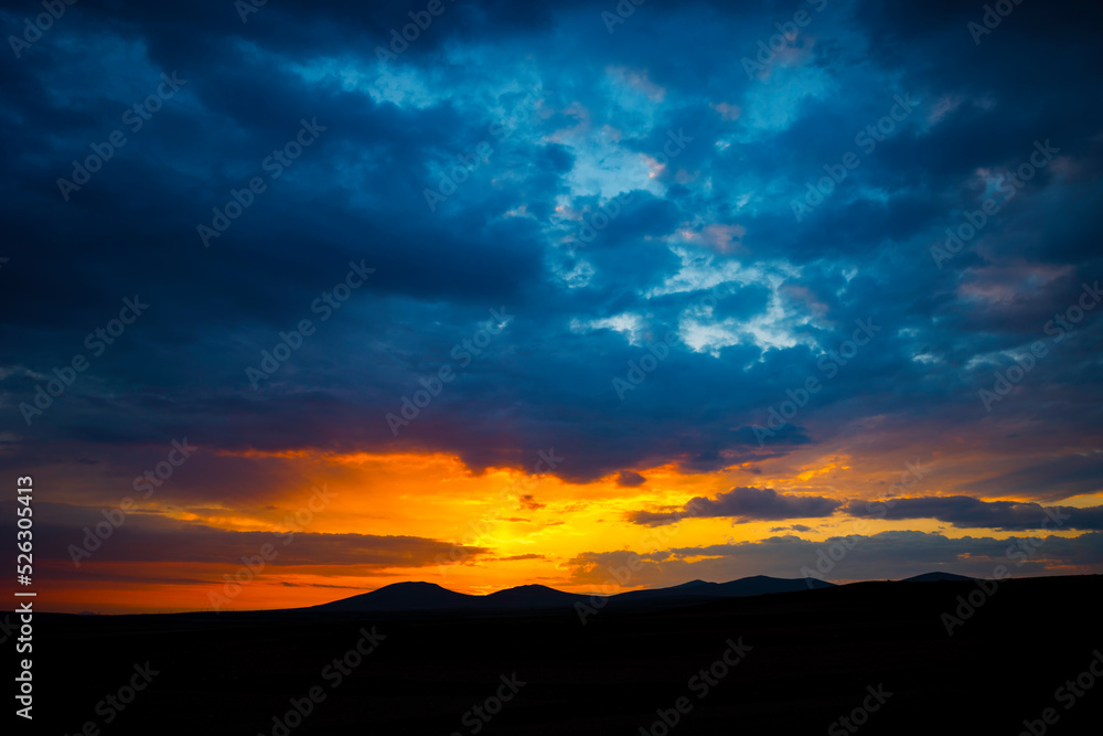 Sunset or sunrise over the hills with dramatic clouds. Peace or heaven concept