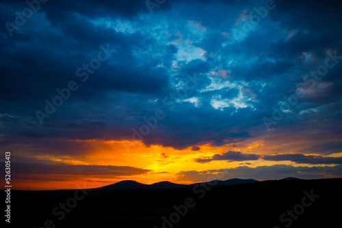 Sunset or sunrise over the hills with dramatic clouds. Peace or heaven concept