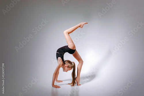 A girl who is engaged in rhythmic gymnastics, a beautiful pretty gymnast in a black elegant leotard leotard. Slender straight legs tightened socks. 