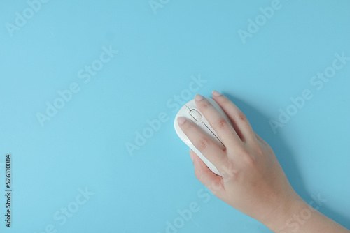 Woman using computer mouse on blue background, top view. Space for text.