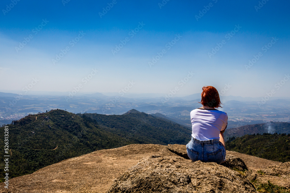 A gril on top of the mountains, looking at the horizon. A gril on top of the mountains, looking at the horizon.