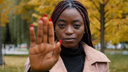 Close-up young serious focused angry african american woman holding palm in front showing stop gesture showing prohibition sign forbidden protect personal boundaries against discrimination violence