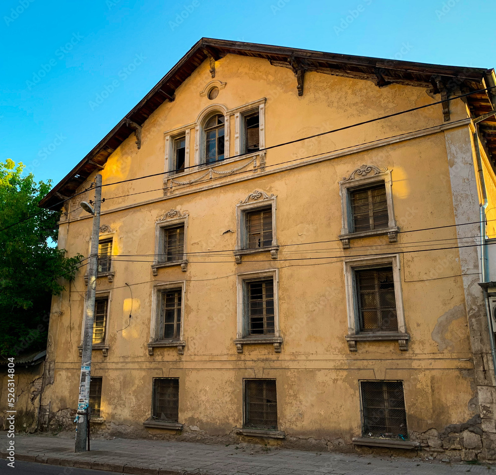An abounded old beautiful house with crumbling
facade. Vintage yellow town mansion with gorgeous
exterior in bad condition.