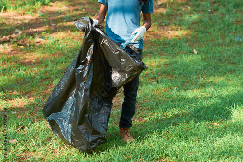 Ethnic gen z male volunteer collects plastic bottle from the forest. Environmental awareness concept.