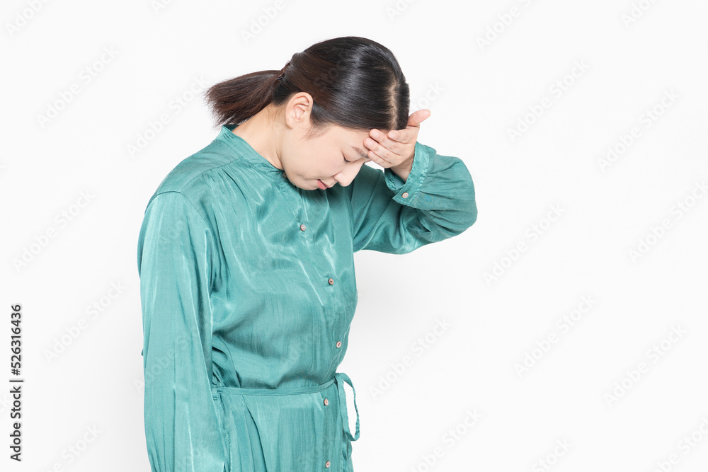 体調不良で頭に手を当てる主婦 体調不良で頭に手を当てる主婦