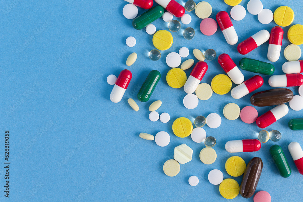 Background of multi-colored pills on a blue background Background of multi-colored pills on a blue background