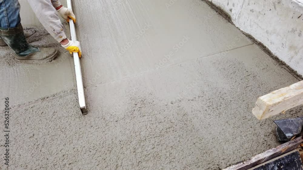 Construction worker uses trowel to flatten cement mortar screed. Concrete works on construction