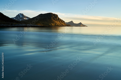 Lofoten sunset landscape on the beach with calm water and mountains in the background