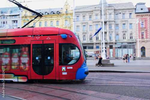 closeup of red and blue tram in the popular Jelacic square in downtown Zagreb. old architectural background. tourism and travel to croatia concept. soft blurred urban background with tourists