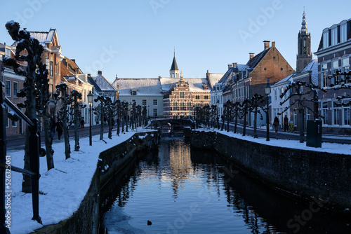 Blue hour winter scene with snow and ice in the canal in old city center of Amersfoort, Netherlands. Overlooking the streets Grote Spui and Kleine Spui with museum Flehite in the background photo