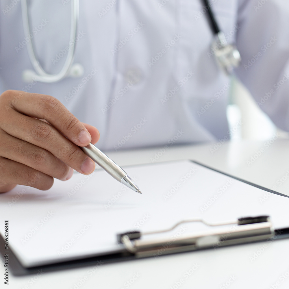Doctor uses a laptop computer to record patient information and write it on a document to prepare for diagnosis in the room of a modern hospital, Emergency assistance and health care concept. Doctor uses a laptop computer to record patient information and write it on a document to prepare for diagnosis in the room of a modern hospital, Emergency assistance and health care concept.