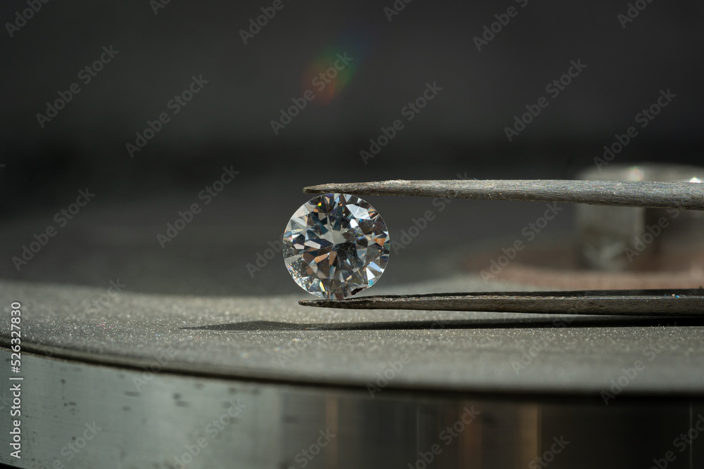close up photo of round Diamond in Tweezers on polishing surface close up photo of round Diamond in Tweezers on polishing surface