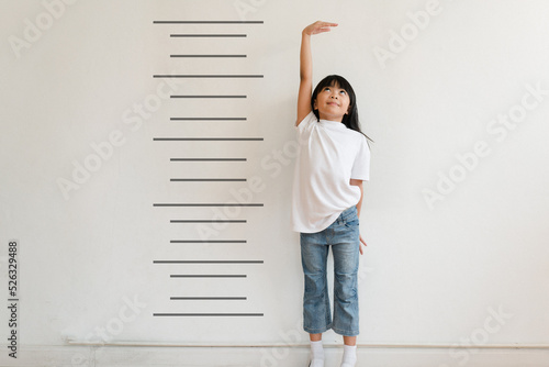 Kid is measuring the growth on the background of wall. Girl power concept.