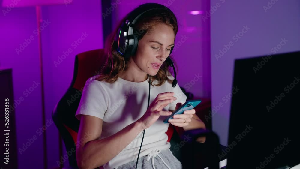 Young beautiful hispanic woman streamer using computer and smartphone at gaming room Young beautiful hispanic woman streamer using computer and smartphone at gaming room