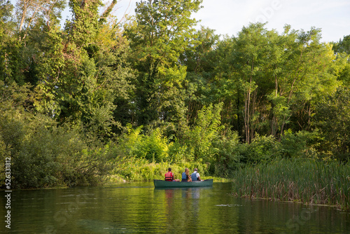 Couple having a canoe experience with a local guide on a natural blue river. Green landscape background
