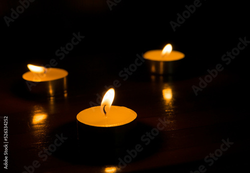 three burning candles on black background