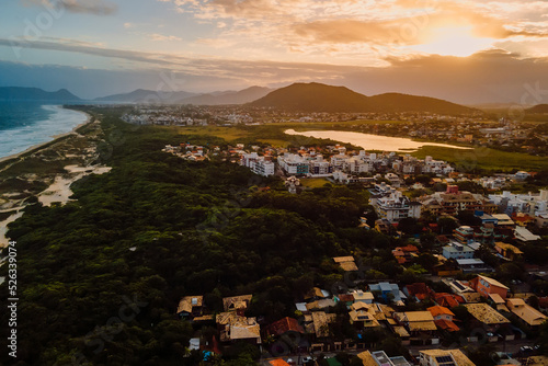 Coastline and town with warm sunset sky in Campeche, Florianopolis. Aerial view