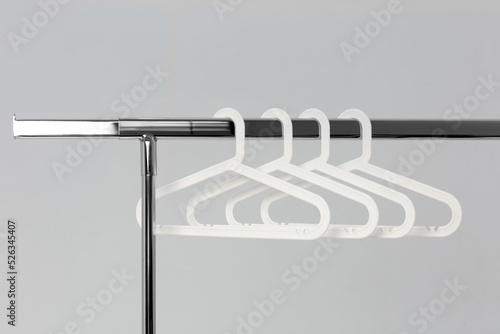Empty wire coat hangers on a simple metal clothing rail inside a white wardrobe
