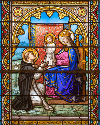 ALAGNA, ITALY - JULY 16, 2022: The Madonna presenting the Rosary to st. Dominic on the stained glass in the church San Giovanni Battista by J. Besnard (1890).