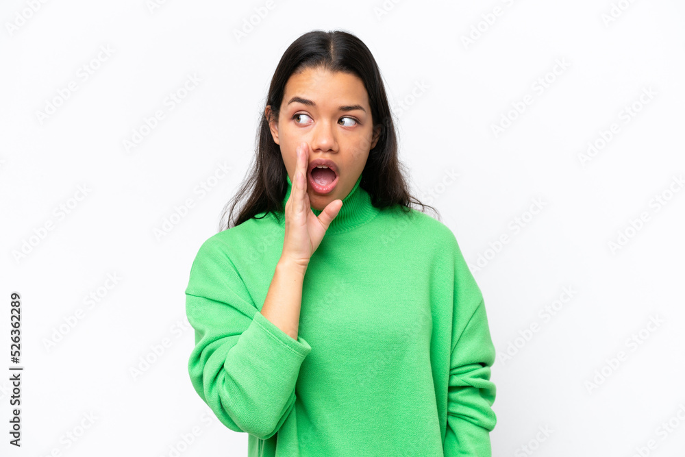 Young Colombian woman isolated on white background whispering something with surprise gesture while looking to the side Young Colombian woman isolated on white background whispering something with surprise gesture while looking to the side