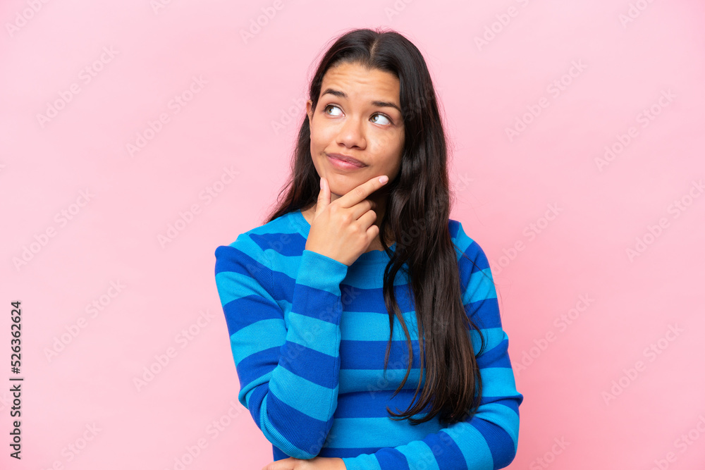 Fototapeta premium Young Colombian woman isolated on pink background having doubts