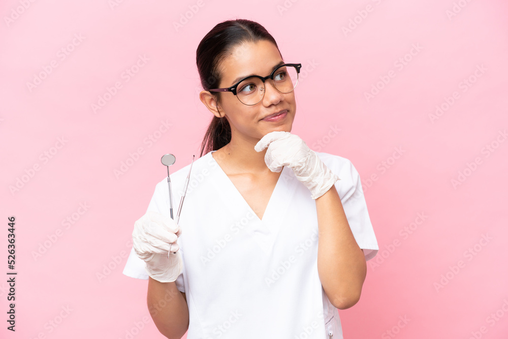 Dentist Colombian woman isolated on pink background and looking up Dentist Colombian woman isolated on pink background and looking up