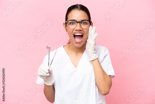 Dentist Colombian woman isolated on pink background with surprise and shocked facial expression