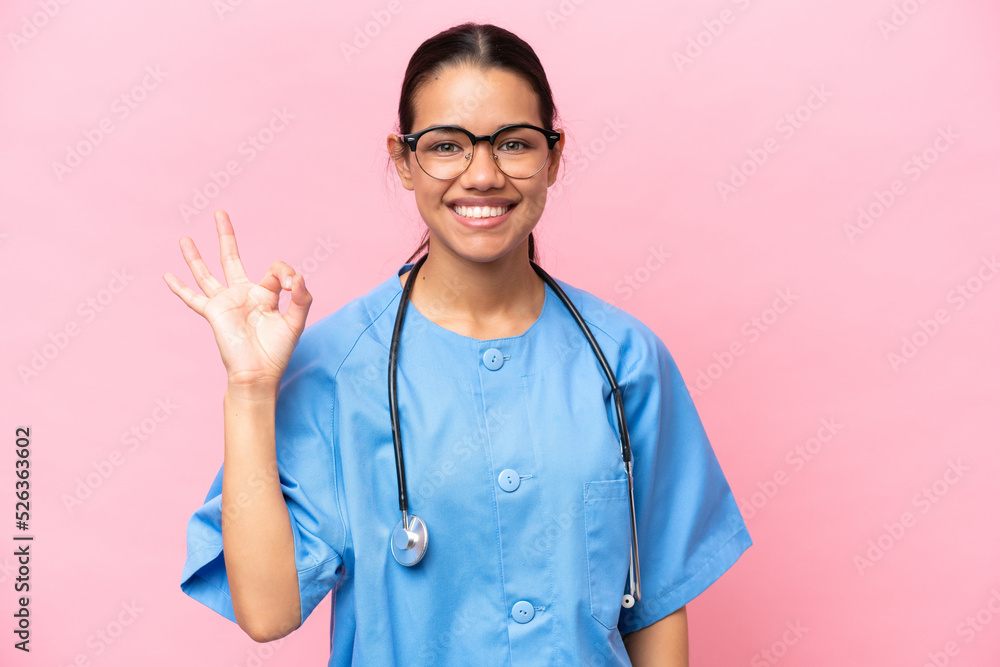 Young nurse Colombian woman isolated on pink background showing ok sign with fingers Young nurse Colombian woman isolated on pink background showing ok sign with fingers