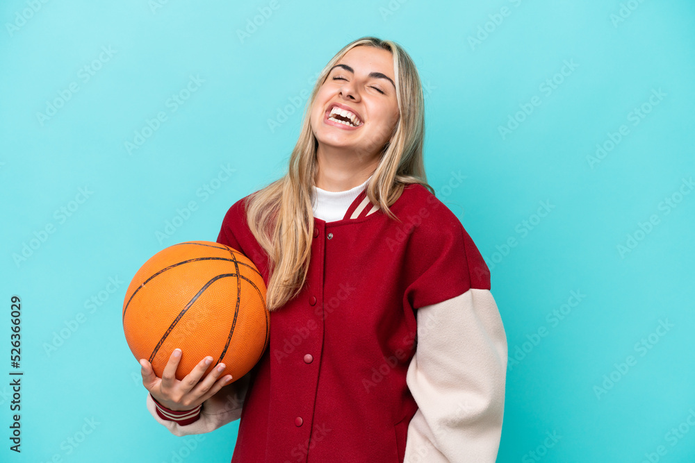 Young caucasian basketball player woman isolated on blue background laughing