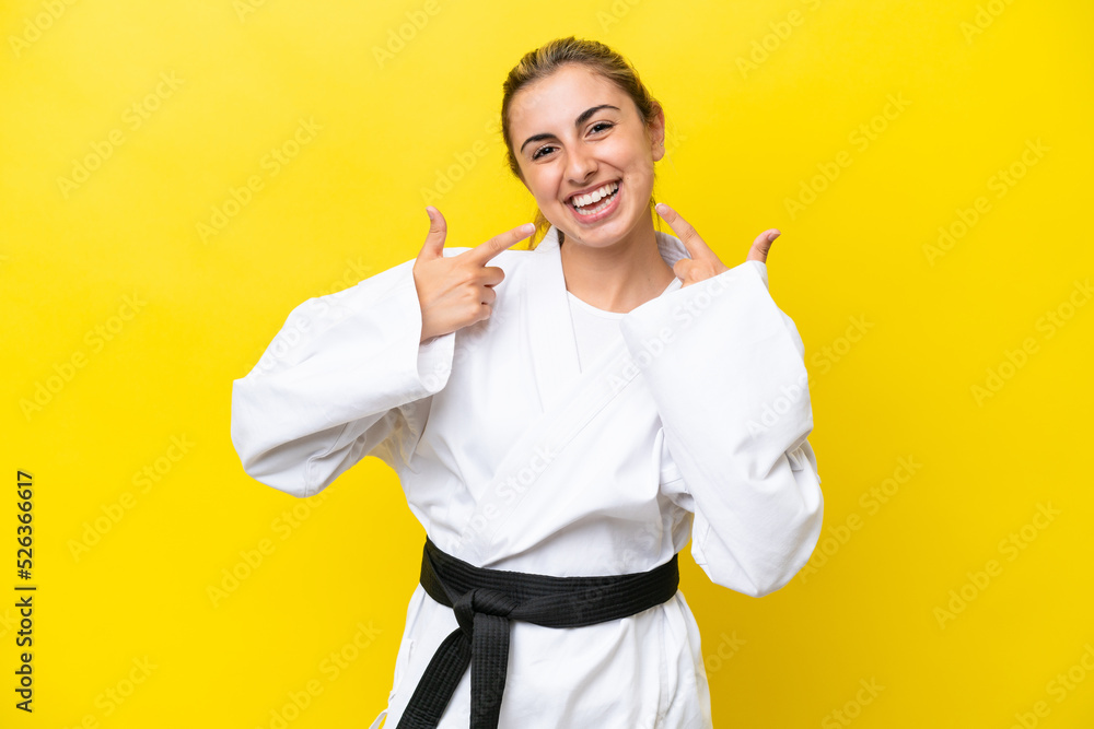 Young caucasian woman doing karate isolated on yellow background giving a thumbs up gesture Young caucasian woman doing karate isolated on yellow background giving a thumbs up gesture