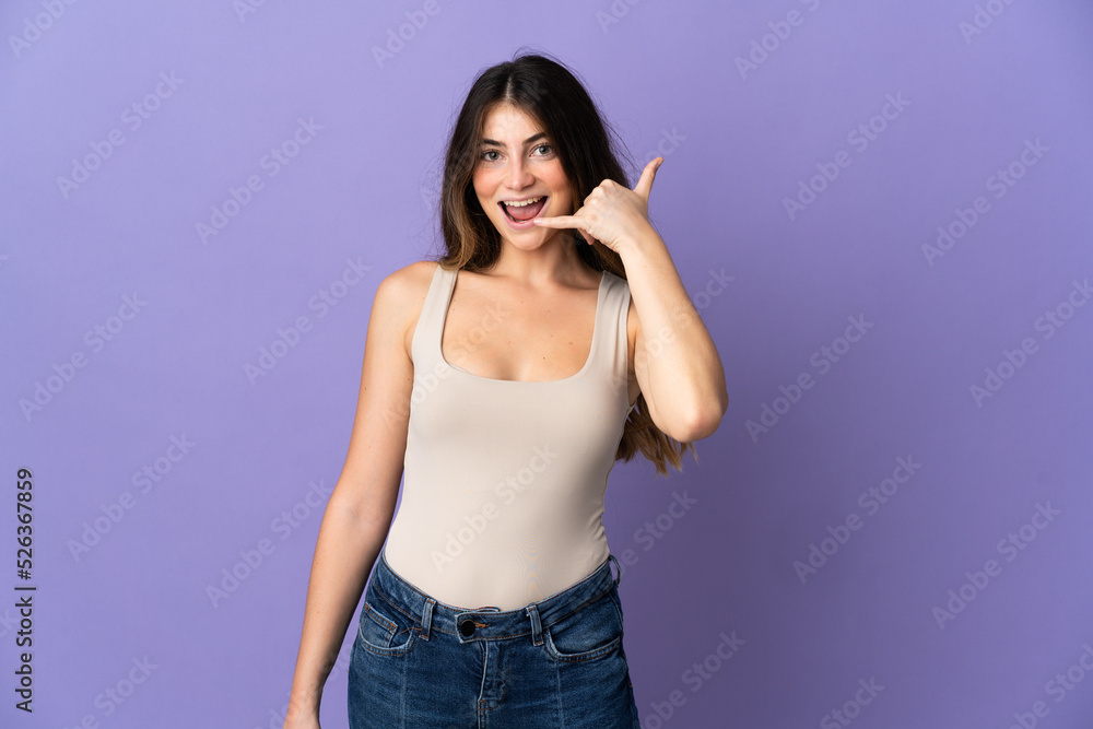 Young caucasian woman isolated on purple background making phone gesture. Call me back sign Young caucasian woman isolated on purple background making phone gesture. Call me back sign
