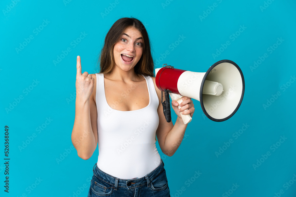 Young caucasian woman isolated on blue background holding a megaphone and pointing up a great idea Young caucasian woman isolated on blue background holding a megaphone and pointing up a great idea