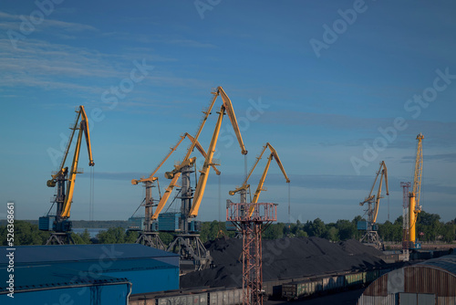 Cranes in an industrial zone in port against the sky by summer day