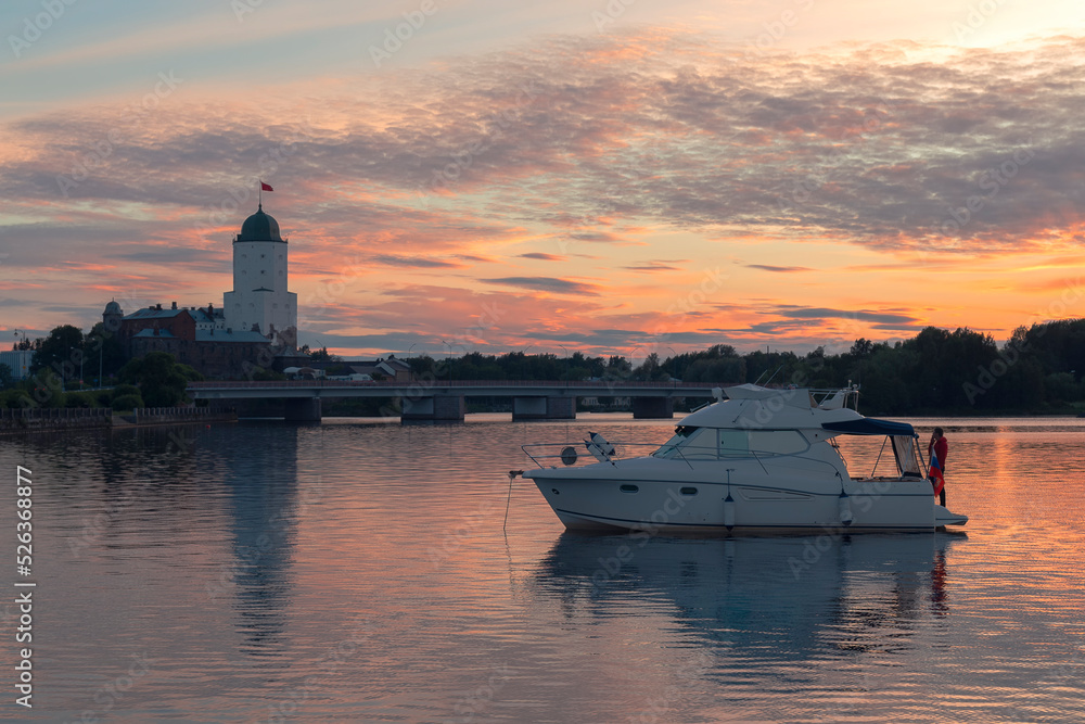 A motorboat against the view of Vyborg castle at summer sunset