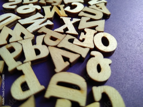 wooden letters of the alphabet scattered on a purple background with space for text