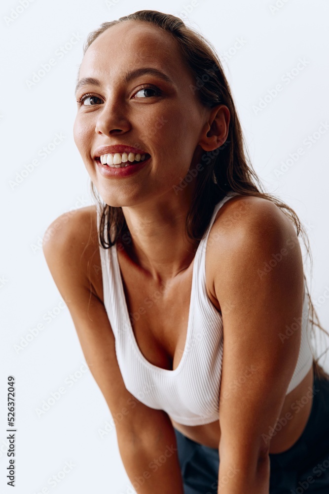 Woman model on white wall background in pants and T-shirt and smiling beautifully at home. Healthy and beautiful facial and body skin Woman model on white wall background in pants and T-shirt and smiling beautifully at home. Healthy and beautiful facial and body skin