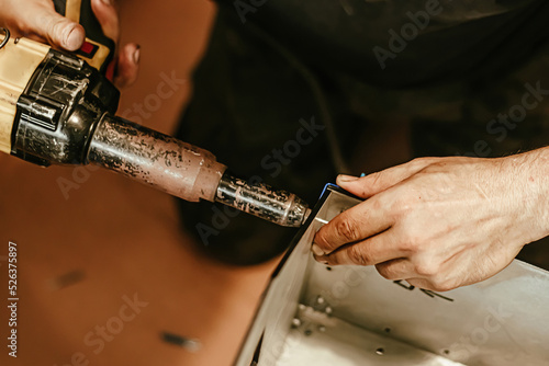 Male worker uses electric riveting gun. Hand holding riveting mashine