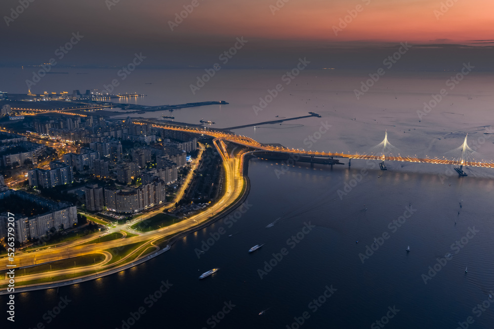 A picturesque sunset over the cable-stayed bridge and Vasilevsky island, passenger sea port, illuminated highway