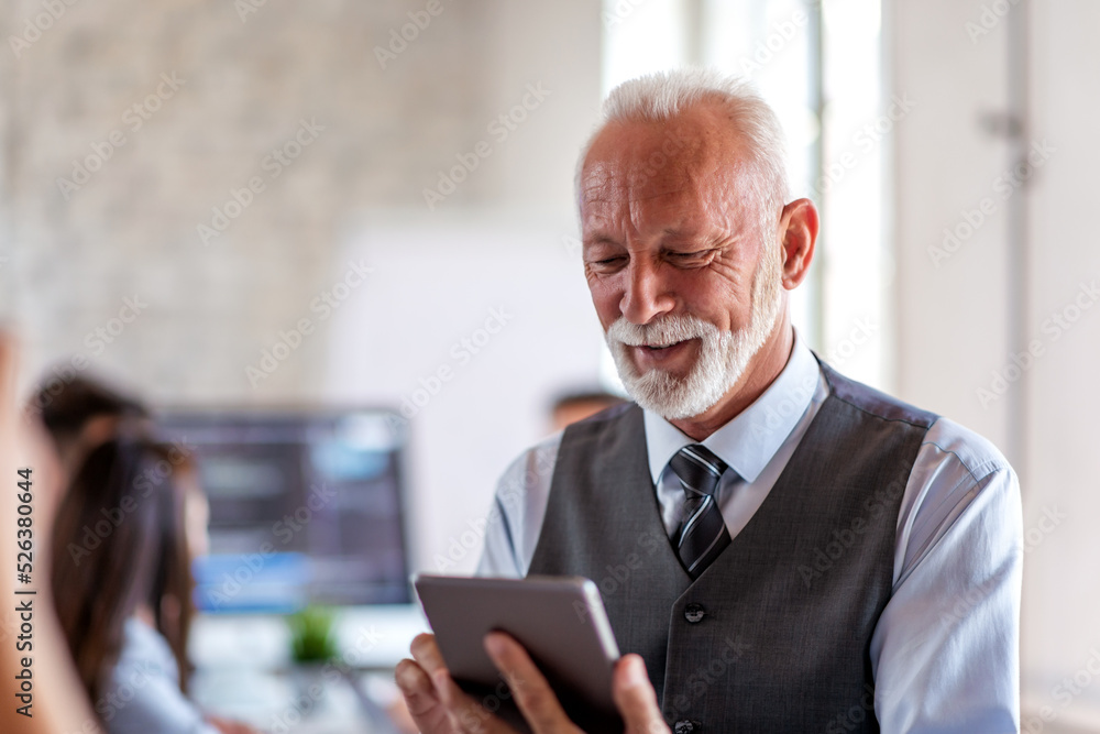 Obraz premium Senior businessman using tablet