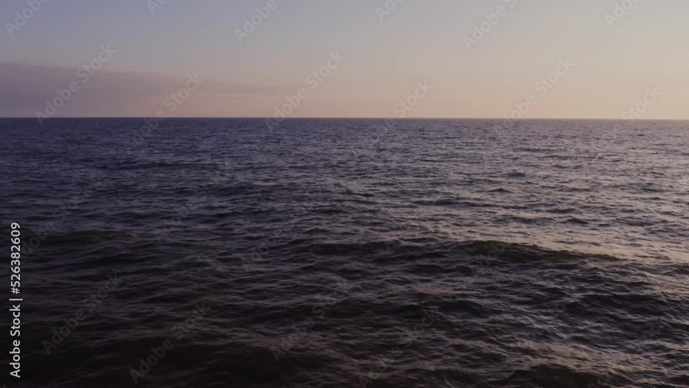 Sea distance with small ripples of waves, no shore, video from a drone. Sunset sky with pink reflections. Sea distance with small ripples of waves, no shore, video from a drone. Sunset sky with pink reflections.