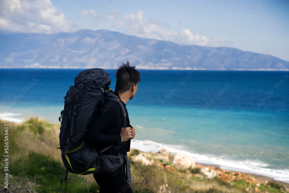 Man is hiking, travelling along the sea coast.